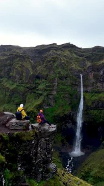 İki maceraperest Mulagljufur Kanyonu 'nun büyüleyici manzarasına hayret eder. Muhteşem bir şelale kayalıklardan yemyeşil bir zemin üzerine dökülür..