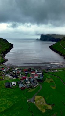 Faroe Adaları 'nın nefes kesici güzelliğini keşfedin. Sahildeki Tjornuvik köyünü sergileyin. Dramatik uçurumlar ve sakin sular sakin bir atmosfer yaratır..