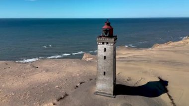 Muhteşem Rubjerknudde deniz fenerini keşfedin. Mavi denize karşı görkemli bir şekilde ayakta duruyor..