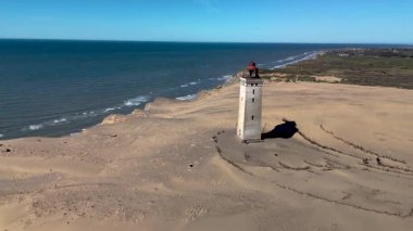 Danimarka 'daki Rubjerg Knude deniz fenerinin nefes kesici güzelliğini tecrübe edin. Altın kumlar ve gök mavisi sularla çevrili..