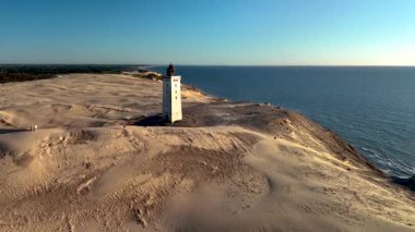 Danimarka 'da Kuzey Denizi' ne bakan kumlu bir kumulda tünemiş Rubjerknudde deniz fenerini keşfedin. Huzurlu manzara doğa aşıkları için mükemmel bir kaçış sunuyor..