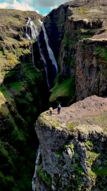 Ziyaretçiler, dramatik uçurumlar ve verimli yeşilliklerle çevrili İzlanda 'daki görkemli Glymur Şelalesine hayran. Bu büyüleyici yerin doğal güzelliğini ve sükunetini hissedin..