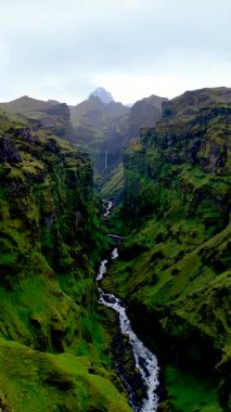 İzlanda 'daki Mulagljufur Kanyonu' nun nefes kesici güzelliğini keşfedin. Yükselen uçurumlar yemyeşil vadileri kucaklarken, el değmemiş bir nehir kanyon boyunca zarif bir şekilde esiyor. Gerçek bir doğal mucize.
