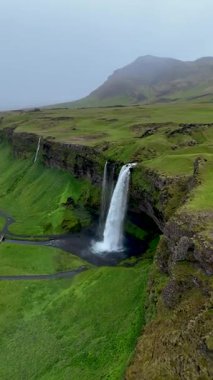 İzlanda 'da Seljalandsfoss şelalesi büyüleyici güzelliğini sergiliyor. Su yeşil tepelerle çevrili bir uçurumdan yuvarlanırken..