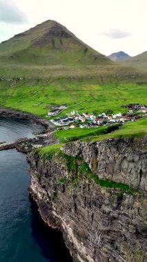 Faroe Adaları 'nın nefes kesen uçurumlarını ve bereketli manzaralarını keşfedin. Gjogv köyü, dramatik dağlar ve zengin yeşil tarlalarla çevrili, ışıl ışıl suların üzerinde zarifçe duruyor..