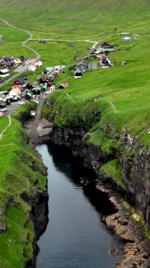 Faroe Adaları 'ndaki yeşil tepeler ve kayalıklarla çevrili Gjogv köyünün huzurlu güzelliğini keşfedin. Sakin sular, cennet manzarasını yansıtır ve güzel bir manzara yaratır..