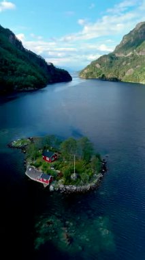 Norveç 'teki büyüleyici Lovrafjorden' ı keşfedin, yemyeşil ve sakin sularla çevrili büyüleyici kırmızı bir kulübe. Doğaya mükemmel bir kaçış ihtişamı.