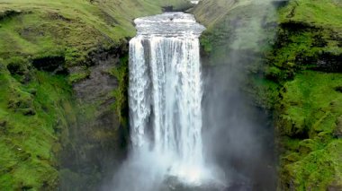 Bereketli yeşilliklerle çevrili engebeli uçurumlardan aşağı dökülen nefes kesici Skogafoss Şelalesine tanık olun..