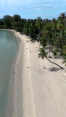 Yumuşak kumlu plajlar, sallanan palmiyeler ve berrak mavi sularla Koh Kood 'un nefes kesici kıyı şeridinin tadını çıkarın. Sahilde salıncakta sallanan bir çift.