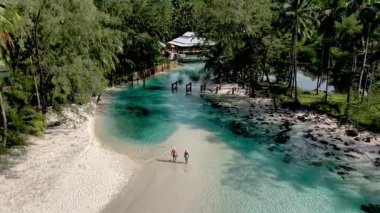 Tayland 'daki Koh Kood Adası' nın el değmemiş kıyı şeridi boyunca yürüyen iki yolcu..