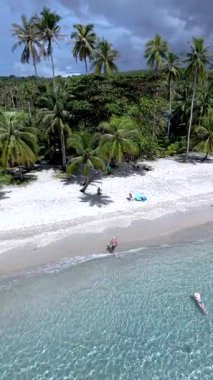 Tayland 'daki Koh Kood Adası' nın dinginliğini tecrübe edin, el değmemiş kumların ışıldayan sularla buluştuğu yer. Palmiye ağaçları rüzgarda hafifçe sallanırken ziyaretçiler huzurlu sahil ortamının tadını çıkarıyorlar..