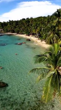 Tayland 'daki Koh Kood Adası' nın büyüleyici güzelliğini keşfedin, kristal berrak sular, kumlu plajlar ve sallanan palmiye ağaçları. Kumsalda yürüyen bir çift adam ve kadın.