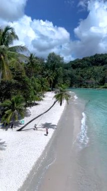 Yumuşak beyaz kumların turkuaz sularla buluştuğu Koh Kood Adası 'nın sakin plajlarını keşfedin. Parlak güneşin altında sallanan gür palmiye ağaçları sahildeki palmiye ağacının altında sallanan bir çift.