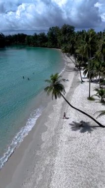 Tayland 'daki Koh Kood Adası' nın sakin atmosferinin tadını çıkarın. Yumuşak beyaz kumların berrak turkuaz sularla buluştuğu yer. Bir çift erkek ve kadın, sallanan avuç içleri altında rahatlar ve doğanın tadını çıkarırlar..