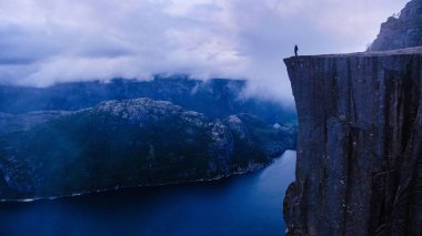 Yalnız bir yürüyüşçü Preikestolen Cliff 'in kenarında duruyor, göz kamaştırıcı Lysefjord' a bakıyor..