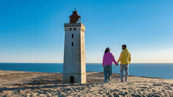 Rubjerg Knude Deniz fenerinde yürüyen bir çift. Deniz feneri Lonstrup Klint, Jutland, Danimarka 'nın tepesinde.