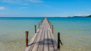 Koh Kood Adası Tayland 'ın çarpıcı turkuaz sularına uzanan ahşap bir iskelenin sakinliğini keşfedin.