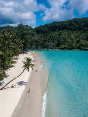 Tayland 'daki Koh Kood Adası' nın huzurlu güzelliğini tecrübe edin. Yumuşak kumlu sahil berrak mavi gökyüzünün altında canlı turkuaz sularla buluşuyor. Bereketli palmiye ağaçları tropik cennet atmosferini güçlendirir..