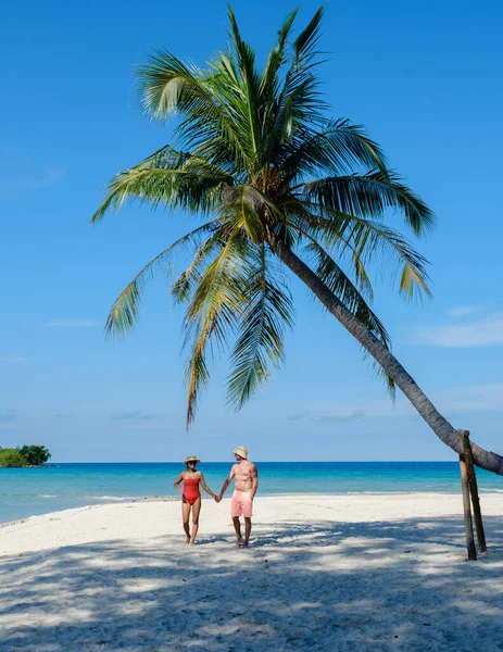 İki mutlu gezgin, sallanan palmiye ağaçları ve turkuaz denizle çevrili Koh Kood Adası 'nın kumlu sahillerinde el ele yürüyor. Tayland 'da rahatlama ve keşif için mükemmel bir gün.
