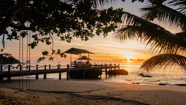 Tayland 'daki Koh Kood Adası' nın sakin sularında gün batımına tanık olun. İskele ufka doğru uzanıyor. Yumuşak dalgalar kıyıya vurur, huzurlu bir atmosfer yaratır..