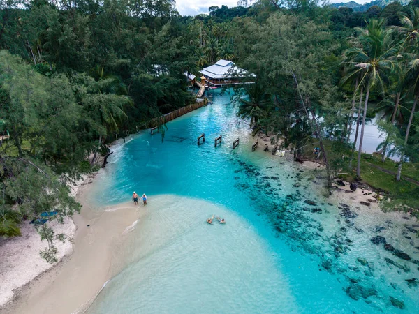 Turkuaz sular Koh Kood Adası 'ndaki kumlu kıyıya hafifçe çarpar. Palmiye ağaçlarıyla çevrili ziyaretçiler güneşli bir günün tadını çıkararak Tayland 'daki bu tropik cennette unutulmaz anılar yaratıyorlar.