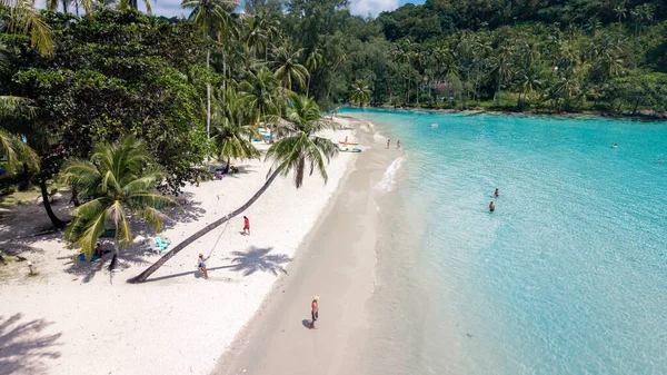 Koh Kood Adası 'ndaki çarpıcı tropikal kıyı şeridi. Güneş banyosu yapanlar sıcak kumun ve renkli suların tadını çıkarırken yemyeşil alanlar manzaranın güzelliğini arttırıyor. Rahatlamak ve keşfetmek için mükemmel bir cennet.