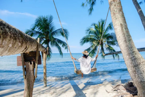 Asyalı bir kadının sallanan palmiye ağaçları ve dingin dalgalarla çevrili sahilde salıncaktan keyif aldığı sakin bir sahne Koh Kood Adası 'nda sergileniyor. Tayland