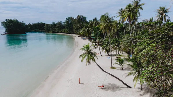 Koh Kood Adası 'ndaki sakin plajda yumuşak beyaz kum ve berrak mavi sular bulunur. Ziyaretçiler tropikal güneşin altında dinlenirken palmiye ağaçları rüzgarda hafifçe sallanıyor. Tayland 'da mükemmel bir kaçış.