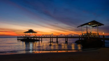 Güneş Koh Kood Adası 'nın sakin sularının üzerinde batarken okyanusa doğru uzanan rıhtımlarla altın renkler gökyüzünü boyar. Rahatlatıcı atmosfer akşam yürüyüşleri ya da deniz kenarında yemek için mükemmel..