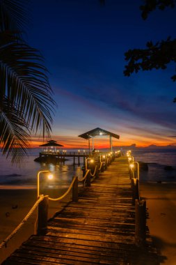 Nefes kesen bir günbatımı Koh Kood Adası 'nda ufukta canlı renkler bırakıyor. Sıcak ışıklarla süslenmiş ahşap iskele, sahilde akşam yürüyüşleri için mükemmel sakin bir atmosfer yaratır..