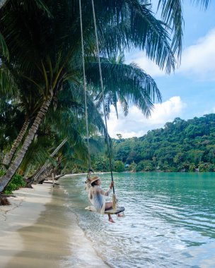 Huzurlu bir an, Koh Kood Adası 'nın sakin sularında sallanan Asyalı bir kadını, el değmemiş plajları ve kıyı boyunca uzanan uzun palmiye ağaçlarıyla yakalıyor. Rahatlamak için mükemmel..