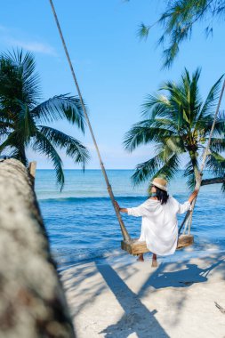 Koh Kood Adası 'nda sakin bir öğleden sonra sahilde salıncaktan keyif alan bir kadınla. Sallanan palmiye ağaçları ve berrak mavi sularla çevrili bu tropikal kaçış Tayland 'da rahatlamak için mükemmeldir.