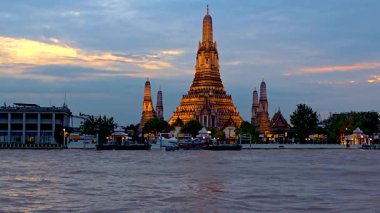 Gün batımı bu ikonik tapınağa altın bir parıltı saçarken Bangkok 'taki Wat Arun' un büyüleyici görüntüsünü keşfedin. Sakin nehir kenarı atmosferi nefes kesici özelliklerini geliştirir..