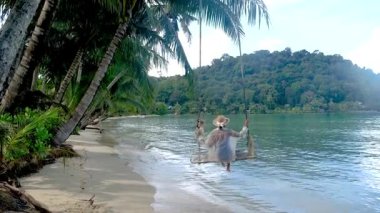Tayland 'daki Koh Kood Adası' nın dingin güzelliğinin tadını çıkarın. Gezginler gök mavisi sularda hafifçe sallanırlar. Bereketli palmiye ağaçları bu sakin kaçışı çerçeveler, rahatlama ve macera için mükemmel.