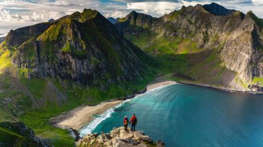 Maceracılar, Lofoten, Norveç 'teki çarpıcı Ryten Kvalvika Sahili Patikası üzerinde panoramik manzaranın keyfini çıkarıyorlar.