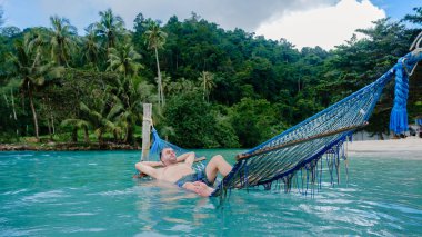 Tayland 'ın Koh Kood kentinin berrak turkuaz sularının üzerinde asılı duran hamakta bir adamın dinlenme yeri açılır.