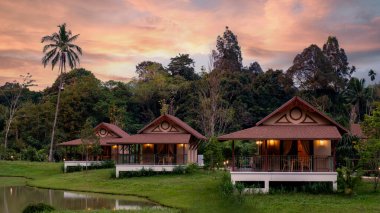 Altın güneş ışığı, güneş batarken Khao Sok Tayland 'da büyüleyici bungalovları yıkıyor. Etrafı canlı doğayla çevrili bu konaklamalar huzur ve rahatlama ve macera için mükemmel bir yer sunuyor..