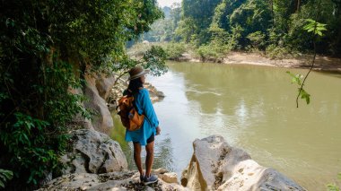 Bereketli yeşilliklerle çevrili bir gezgin Tayland 'ın Khao Sok kentindeki sakin nehire bakıyor. Bu huzurlu an, doğadaki maceranın özünü yakalar..
