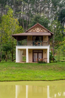 Tayland 'ın Khao Sok kentindeki sakin suların yanında canlı yeşilliklerle kaplanmış büyüleyici bir villa var. Bu resim gibi manzara, doğanın güzelliği arasında huzurlu bir geri çekilme sunuyor..