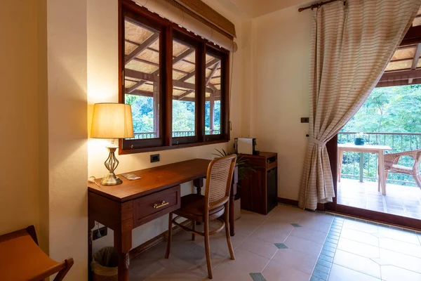 Ahşap bir masa ve lambanın bulunduğu rahat bir çalışma alanı yemyeşil yeşilliğe göz yumar ve Tayland 'da barışçıl bir ortam yaratır. Rahatlamak ve ilham vermek için mükemmel..