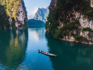 Kireçtaşı tepeleri ve yemyeşil yemyeşil ile çevrili Cheow Lan Gölü 'nün sakin sularını keşfedin. Khao Sok Tayland 'da uzun kuyruklu bir çift.
