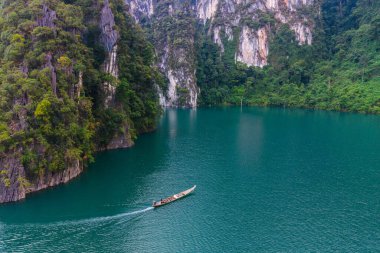 Uzun kuyruklu bir tekne Tayland 'ın Khao Sok kentindeki Cheow Lan Gölü' nün sakin sularında sorunsuzca süzülüyor..