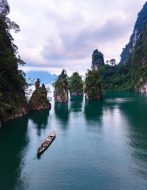 Khao Sok Tayland 'daki Cheow Lan Gölü' nün çarpıcı güzelliğini keşfedin. Görkemli kireçtaşı oluşumları zümrüt sularından dramatik bir şekilde yükseliyor..