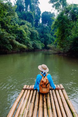 Tayland, Khao Sok 'ta bir bambu salında huzurlu bir an. Bereketli yeşilliklerle çevrili bir gezgin, doğayla bütünleşen ve macerayı kucaklayan huzurlu nehrin tadını çıkarır..