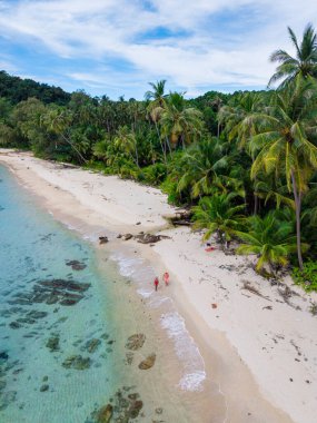 Palmiye ağaçlarının çerçevelediği sakin bir plaj boyunca yürüyen iki ziyaretçi olarak Koh Kood Adası 'nın çarpıcı güzelliğini keşfedin. Temiz su ve yumuşak kum Tayland 'daki bu tropik cennette rahatlamaya yol açar.
