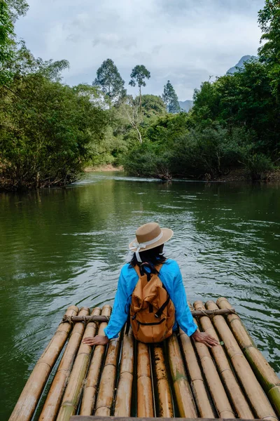 Bir gezgin, Khao Sok Tayland 'da yemyeşil yemyeşil bir salda oturur. Huzurlu su, sakin atmosferi yansıtır, doğanın harikulade keşiflerini davet eder..