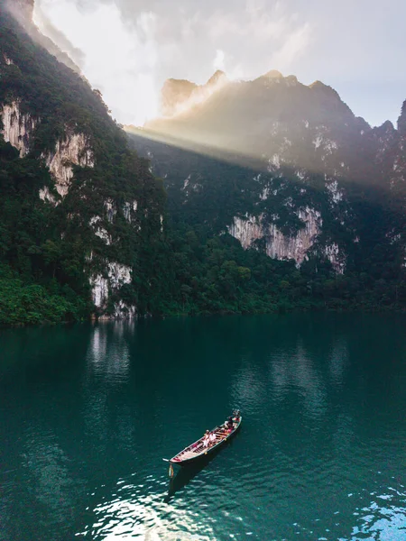 Güneş suyun üzerinde dans ederken Khao Sok, Tayland 'daki Cheow Lan Gölü' nün dingin güzelliğini tecrübe edin..