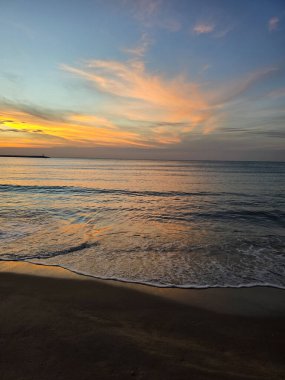 Tayland 'da Baan Krood Sahili' nin üzerinde güneş batarken gökyüzünü canlı renkler kaplıyor. Yumuşak dalgalar kıyıya vurur. Huzurlu bir atmosfer yaratır. Rahatlama ve yansıma için mükemmel..
