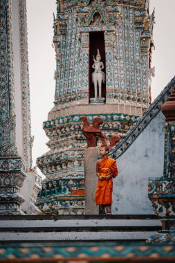 Bangkok, Tayland, 19 Kasım 2025. Genç bir keşiş Wat Arun 'da huzur içinde duruyor. Etrafı karmaşık mimari ve sakin bir atmosferle çevrili. Tayland kültürünün ve maneviyatının güzelliğini yansıtıyor..
