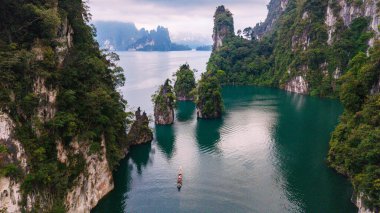 Khao Sok, Tayland 'daki Khao Lan Gölü' nün sakin sularını keşfedin. Yüksek kireçtaşı kayalıkları ve yemyeşil alanlarla çevrili. Yalnız bir tekne sakin gölde huzur içinde süzülür, maceraya davetiye çıkarır..